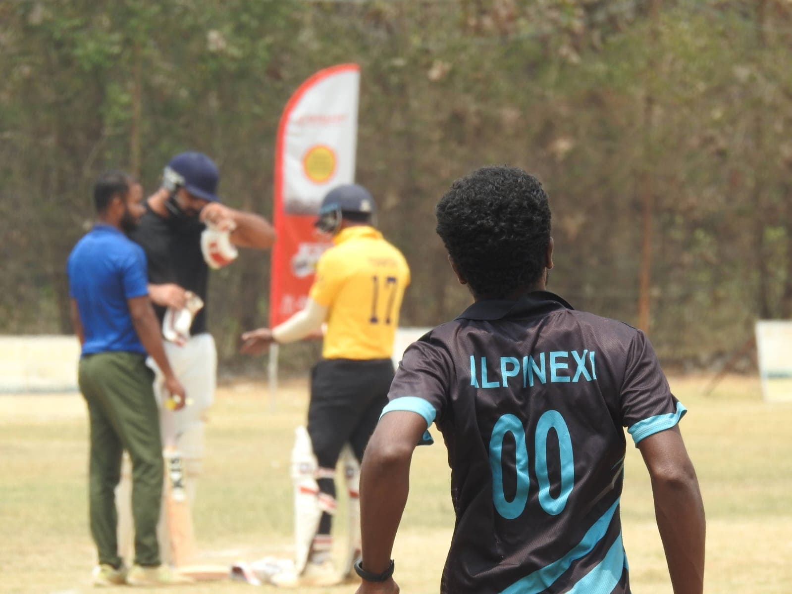 Axi Club fielder in a club shirt watching the batter from the outfield