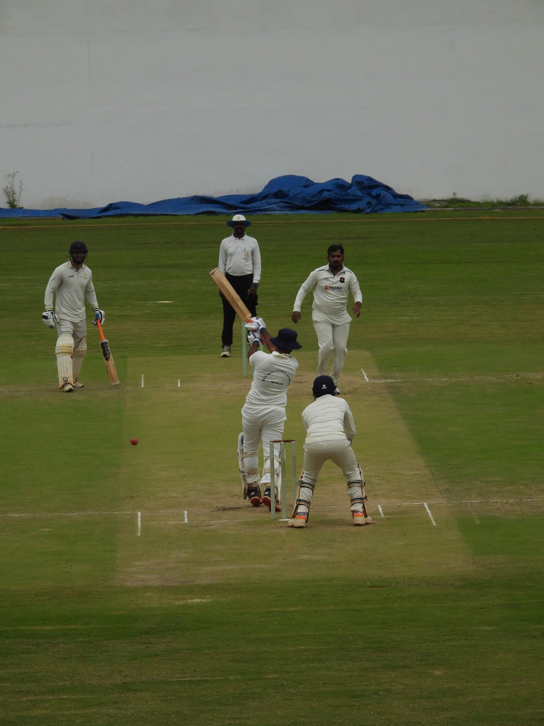 Axi Club batter facing a delivery in a whites match, with the umpire and wicket-keeper in position