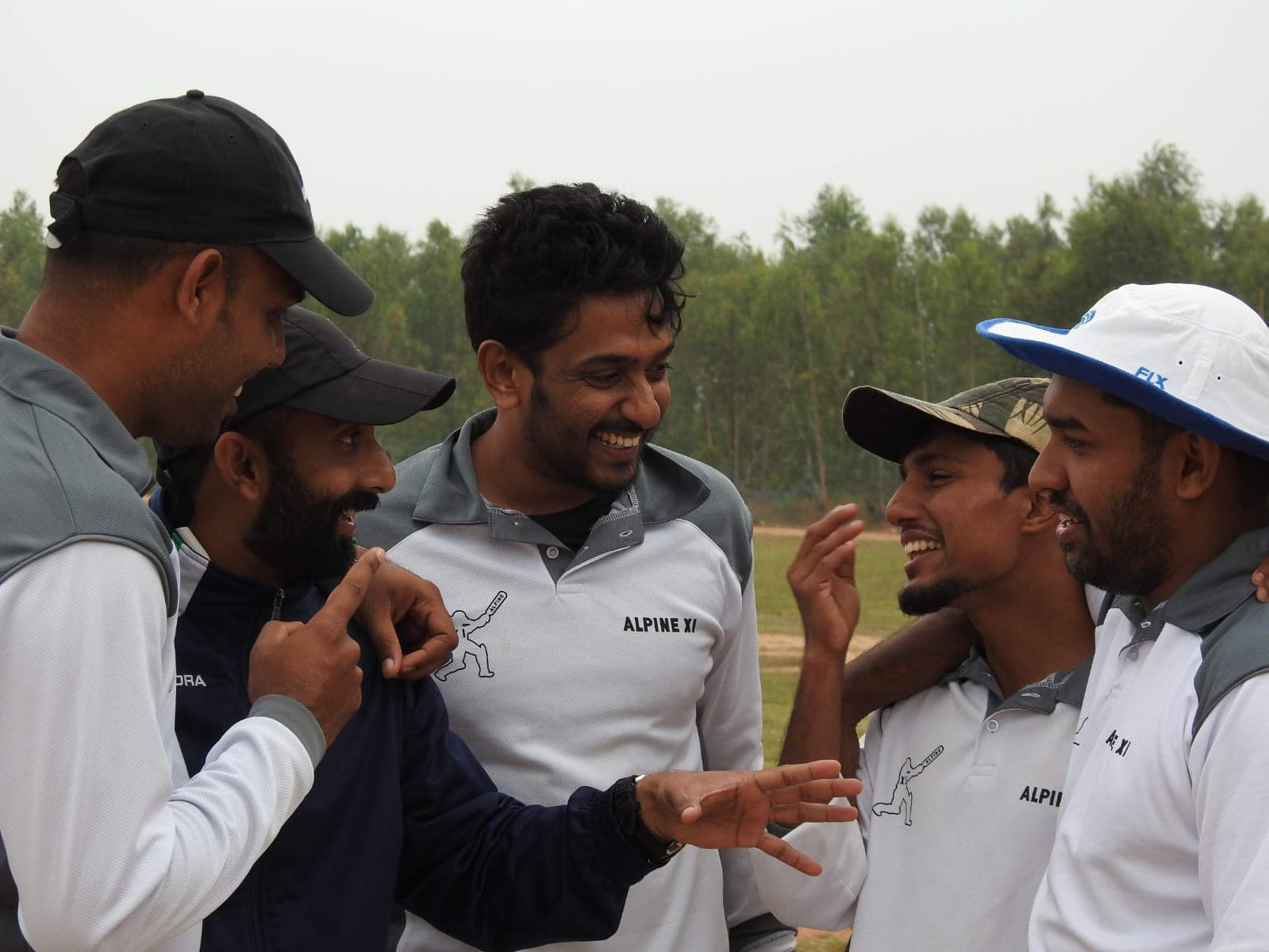 Axi Club players in club polos laughing together on the boundary before a match
