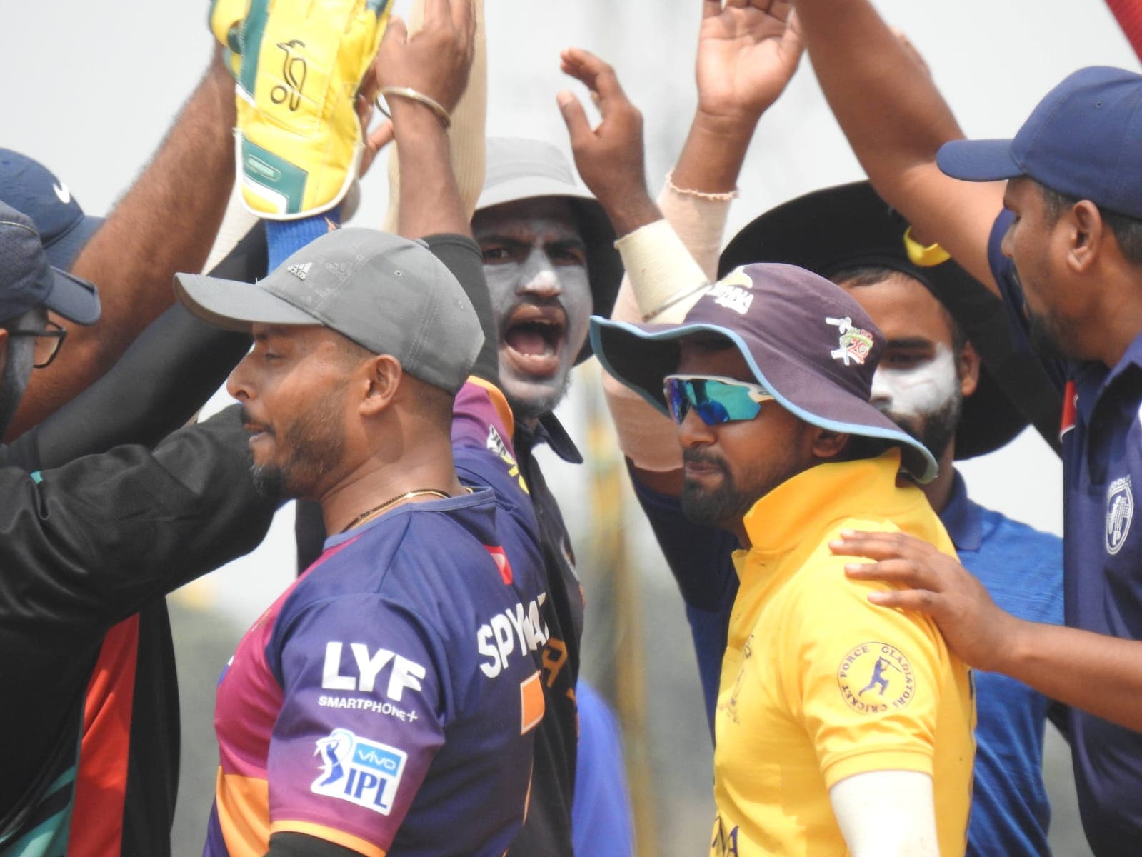 Axi Club players celebrating a wicket with hands raised in a close huddle